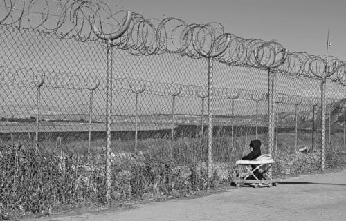 Geçici Barınma Merkezi, temporary accommodation center, baby, confined, curious, looking over, barbed wire, kilis, turkey, türkiye, turkiye, B&W